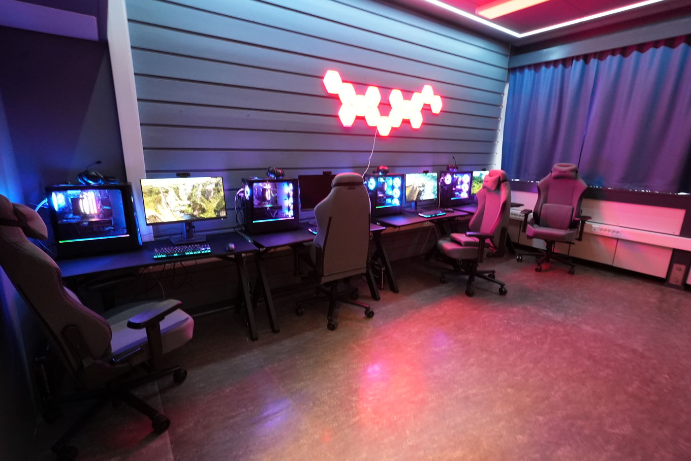 et rom med skrivebord og stoler med datamaskin på